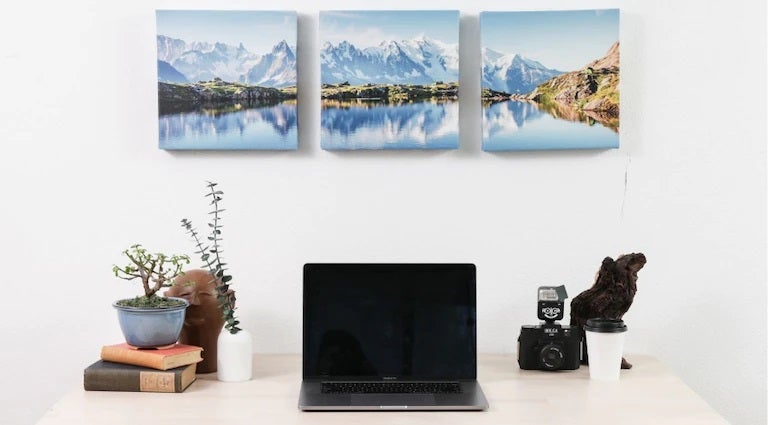 Person decorating a wall with a custom canvas print in a bright living space